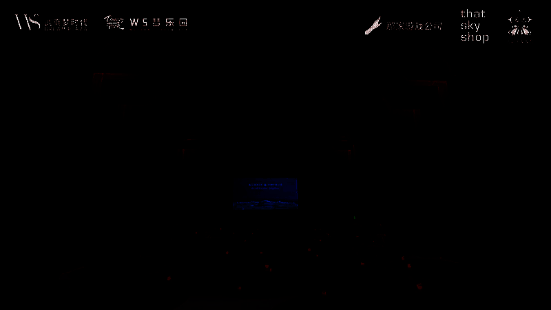 百人巡游队伍手持道具走过活动现场，背景是绚丽多彩的气球雨