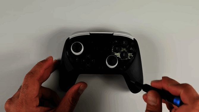 iFixit主播正在拆解NS2 Pro手柄，桌面摆放着各种工具与零件