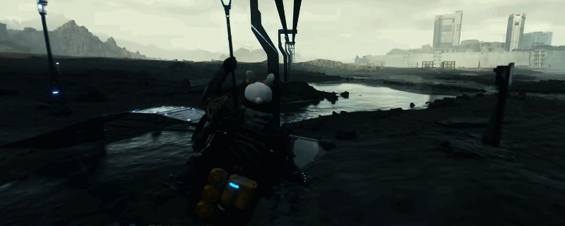 《死亡搁浅2》游戏内实机画面，展示主角手持消音狙击枪准备射击的场景