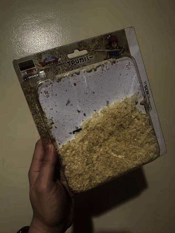 3DS保护壳粉化后内部残渣特写，塑料碎屑布满盒内