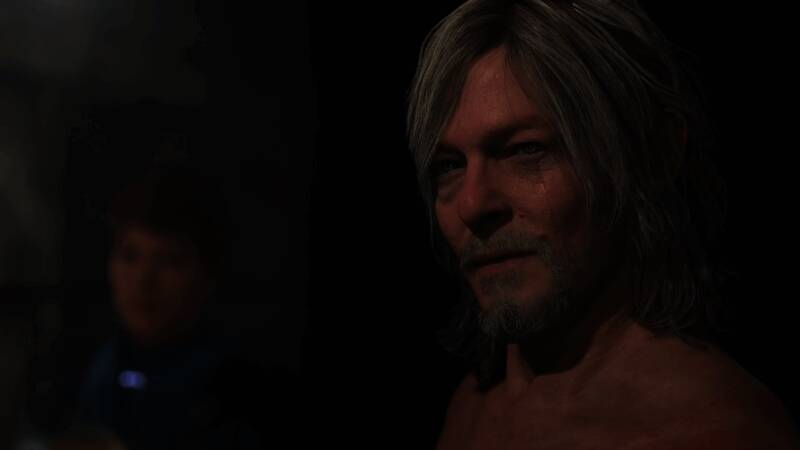 小岛秀夫接受采访现场照片，背景为《死亡搁浅2》宣传海报