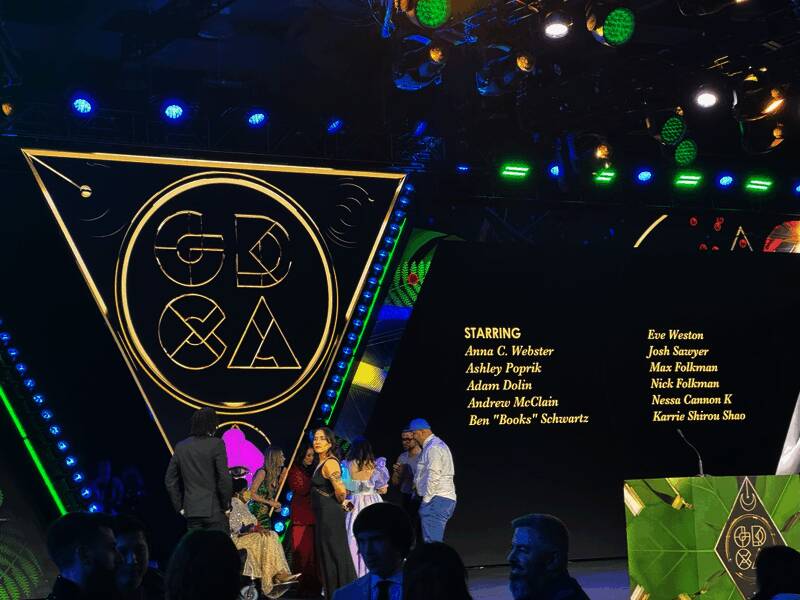 多位游戏开发者在会议室内讨论，背景显示游戏界面与数据图表