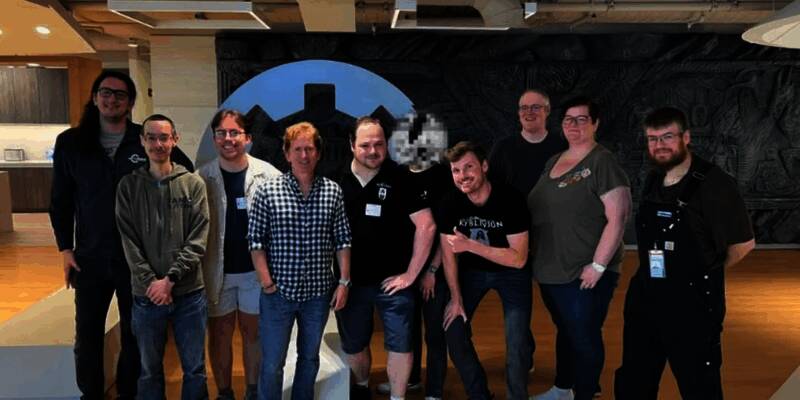 《Skyblivion》团队成员与B社员工在工作室内合影，背景可见多款经典游戏周边