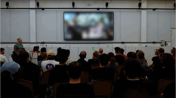 Ninja Theory官方Instagram截图，显示一块模糊的游戏画面屏幕，开发团队成员正围绕观察