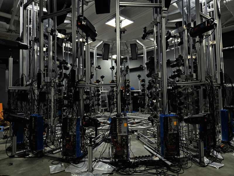 工作人员正在操作3D扫描仪器，屏幕上显示人物建模细节