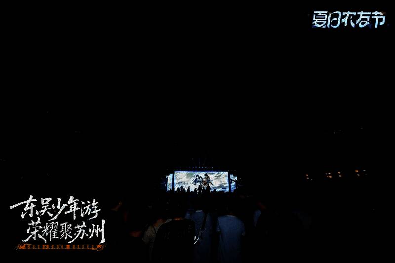 游客在平江路手持王者主题扇子拍照，背景是古街与游戏角色立牌