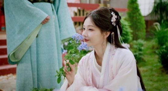 李一桐身穿古风服饰站在田埂上，笑容恬淡，背景是金色麦浪与袅袅炊烟