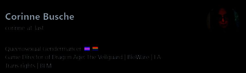 开发团队合影，Corinne Busche站在中央，背景为BioWare工作室标志与《龙腾世纪》LOGO