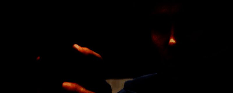 机械战警站立于废墟城市之中，身穿金属装甲，手持Auto-9手枪，背景是燃烧的底特律夜景