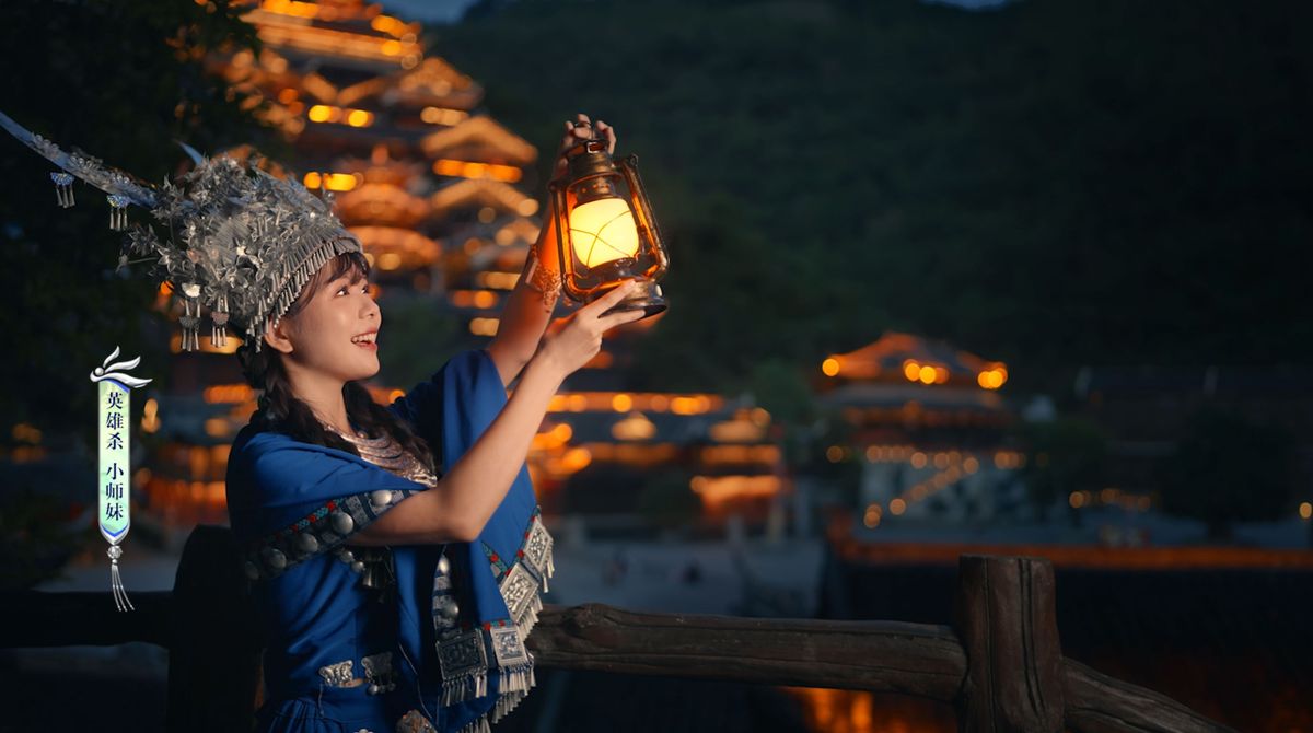 小师妹身着苗族传统服饰，头戴银冠，站在九黎城城门前微笑招手