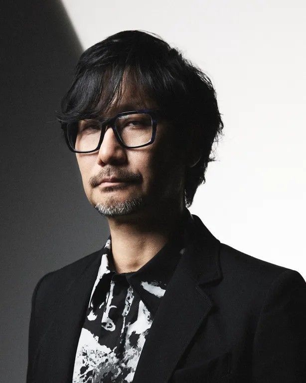 小岛秀夫在工作室中沉思的画面，背景布满《死亡搁浅》游戏元素与电影分镜草图