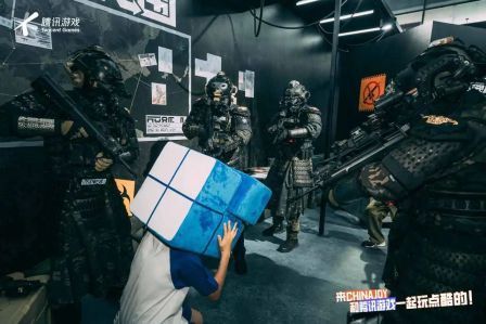 《暗区突围》角色模型包围魔方吉祥物小魔方的趣味场景，玩家举着‘版本更新了吗’‘策划在哪’等搞笑标语