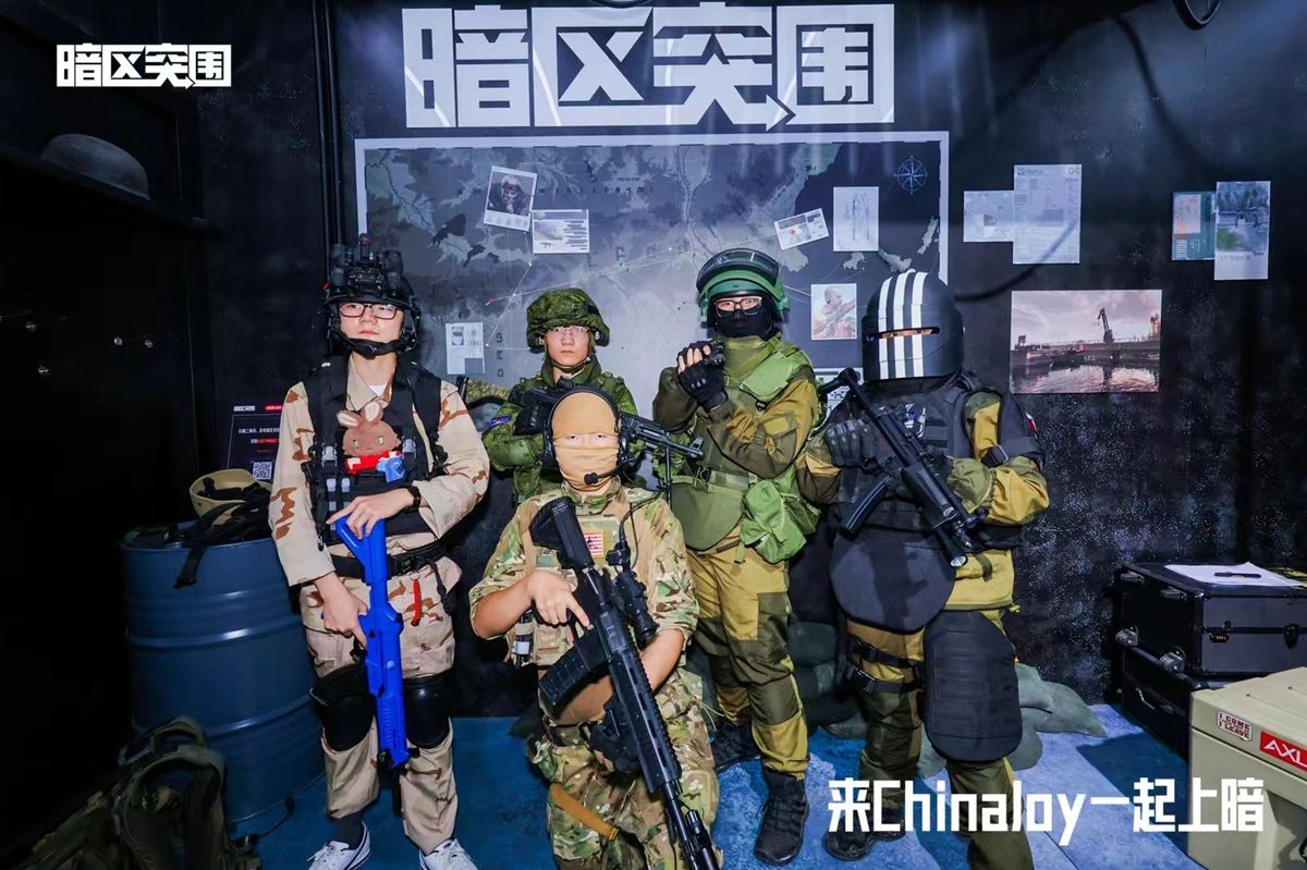 玩家身穿战术装备在撤离点布景区合影，背景为‘撤离成功’LED字样