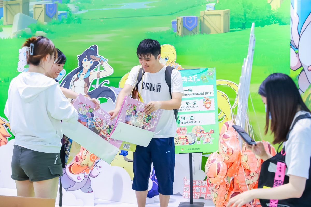 玩家手持《云海之下》沙球周边手办合影，背景为展台幻兽展示墙