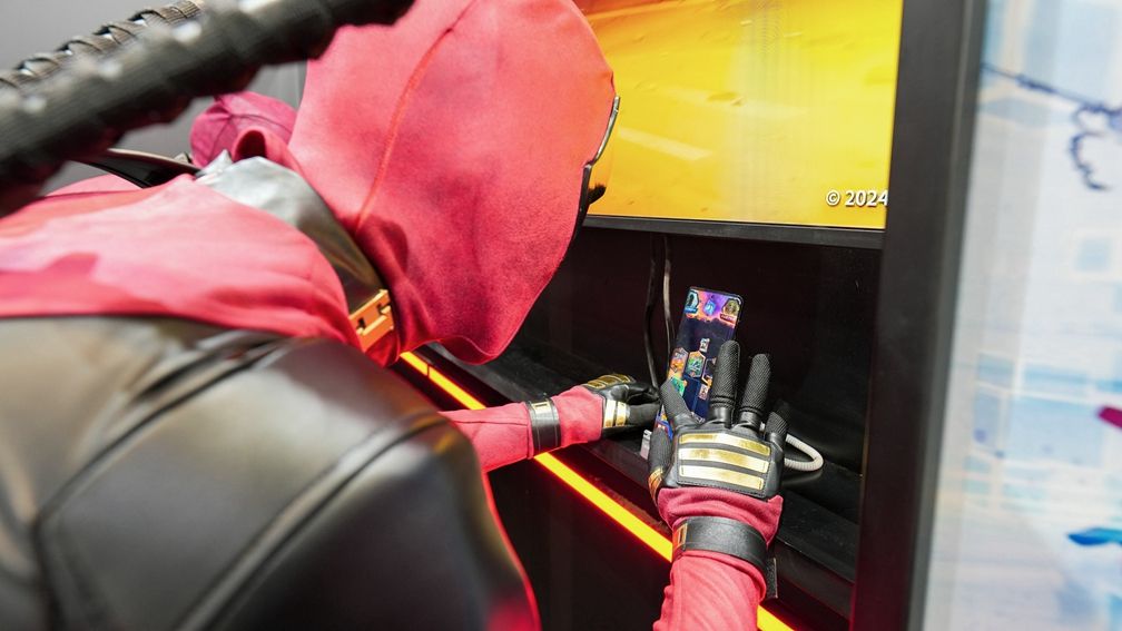 死侍Coser与玩家在牌桌前对战《漫威终极逆转》，背景是炫酷的漫威主题灯光与展板