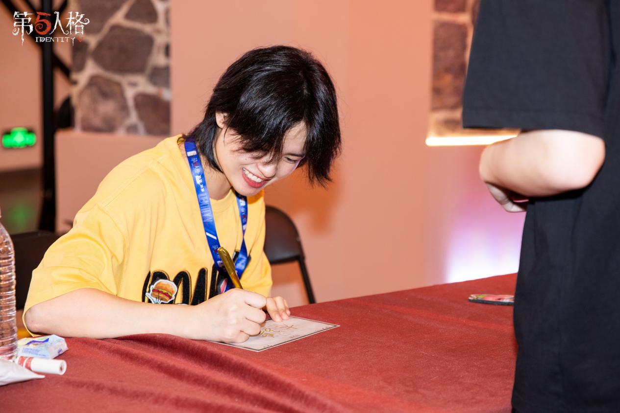 粉丝排队等待嘉宾签售，现场氛围热烈，展台布置充满游戏元素