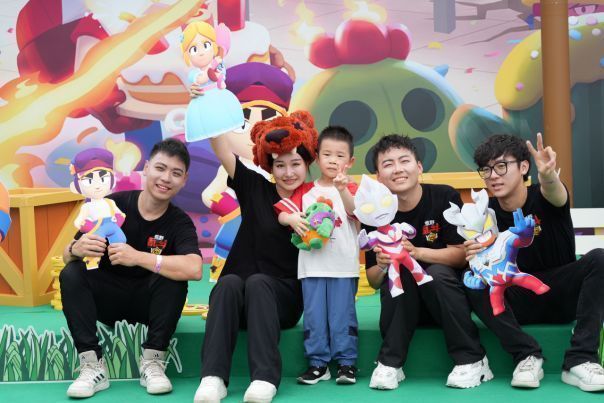 家长与孩子在活动现场参与水枪游戏，场面欢乐