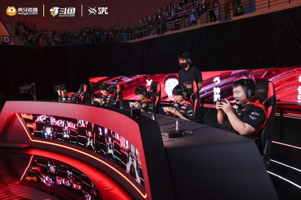 粉丝在应援墙前合影留念，手持战队旗帜与灯牌热情助威