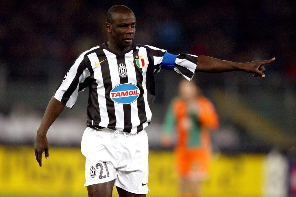 图拉姆身披法国队战袍高举世界杯奖杯， teammates 围绕庆祝，烟花在夜空中绽放