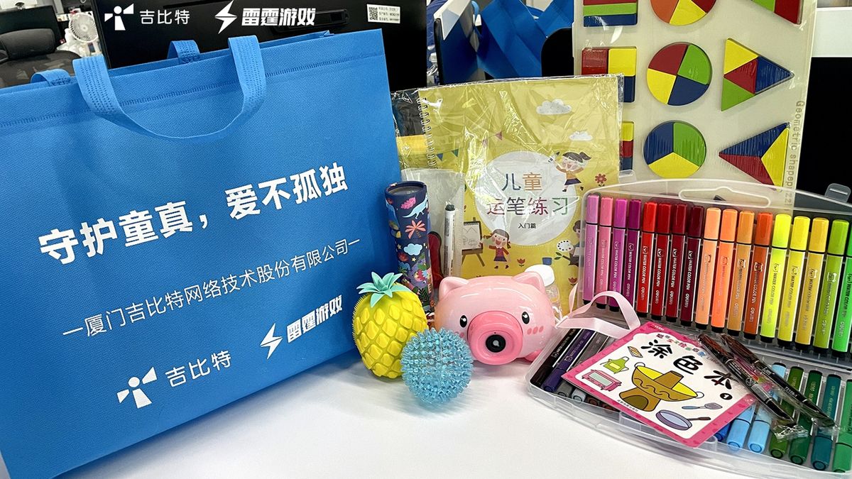 吉比特&雷霆游戏团队参与公益活动合影，成员手持公益标语牌，背景为乡村校园