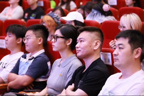 多位腾讯游戏专家在讲台上与学生互动交流，背景屏幕显示游戏开发流程图