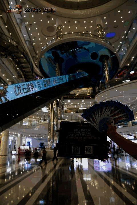 主播在直播间介绍联动周边产品，背景为游戏与机甲联动海报