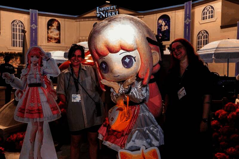 德国玩家在《无限暖暖》展台前与大熊猫主题角色合影，笑容灿烂