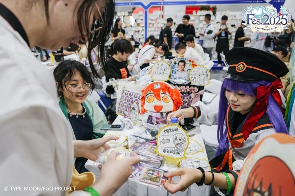 御主交流区内玩家围坐畅聊，桌上摆放着FGO角色徽章和周边