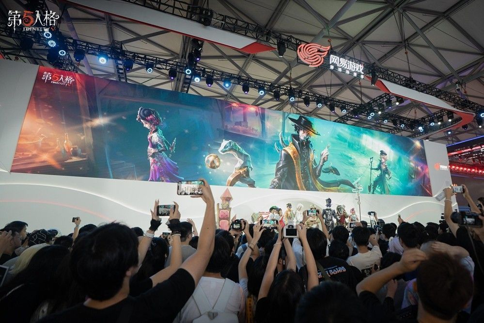 玩家在舞台上开心展示获得的周边礼包，背景是《第五人格》LOGO和绚丽灯光