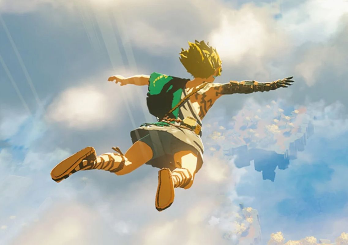 岩田恭明在任天堂工作时期的官方照片，面带微笑，身穿正式西装，背景为任天堂标志性LOGO