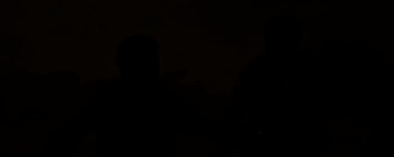 《四海兄弟：故乡》中BOSS战场景，主角与托里西阁下在昏暗仓库内对峙，周围散落木箱，气氛紧张