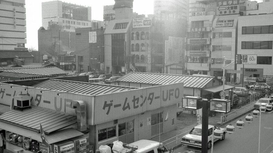 日本街头常见的抓娃娃机排列场景，色彩缤纷的机器内摆放着各种动漫角色玩偶