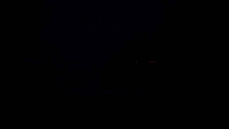 夜晚雪原上，一头灰狼悄然逼近营地，火光映照出其发光的眼睛