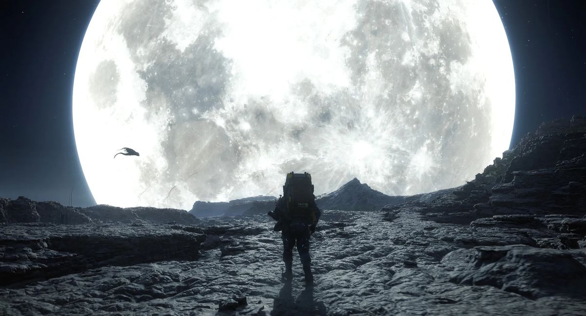 小岛秀夫在伦敦活动现场与粉丝互动的场景，背景展示着《死亡搁浅》系列游戏画面