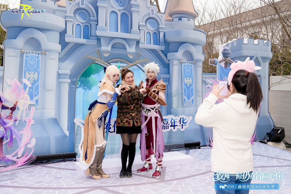 嘉年华室内试玩区全景，数十台高配电脑整齐排列，上百位玩家专注操作，研发人员穿梭其间热情答疑，屏幕上展现无缝衔接的草原与城镇景观