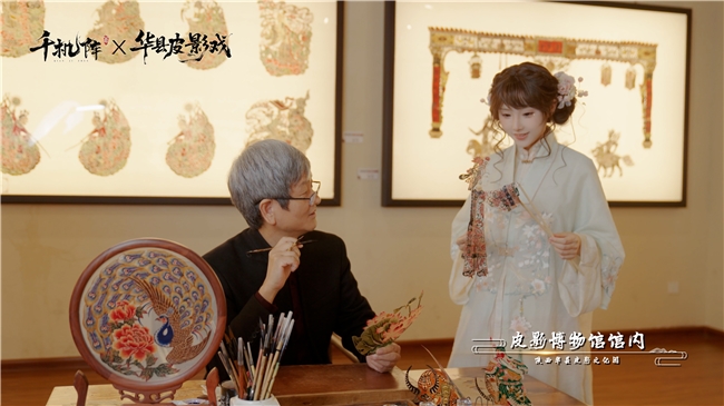 华县皮影戏联动纪录片截图：薛宏权大师在工作台前手持皮影偶，向镜头展示霍去病角色皮影的关节雕刻细节与透光效果