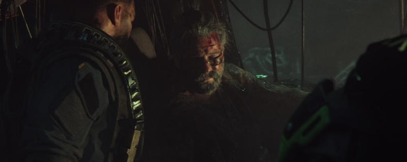 《毒液突击队》游戏内俯视角战斗场景：主角站在狭窄街道中央，两侧堆满红色炸弹桶，远处密密麻麻的僵尸正蜂拥而至，画面充满紧张动感